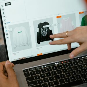 Close-up of hands interacting with a shopping website on a laptop screen indoors.